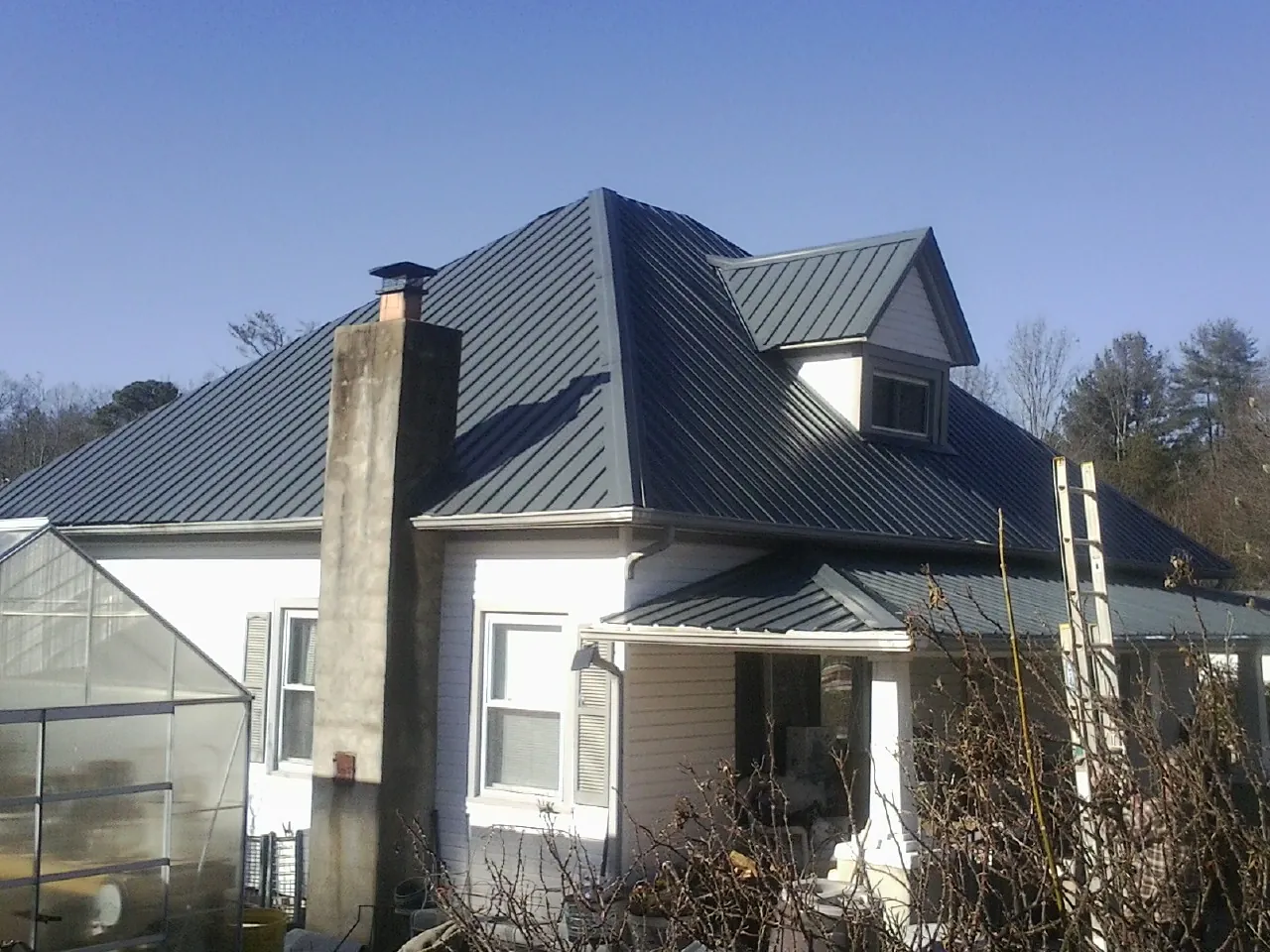 Dark blue standing seam metal roof on a white farmhouse with dormer — Slate & Tile Roof Repair by Roofing Brothers in Bodega Bay