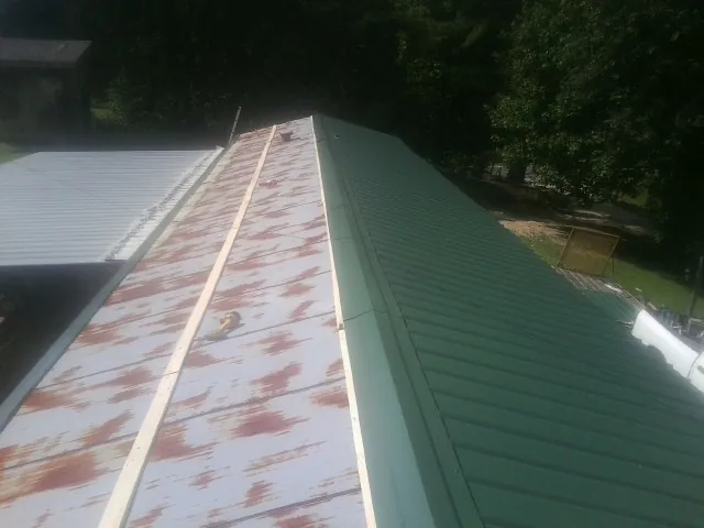Old rusted panels beside newly installed green metal roofing — Wind Damage Roof Repair by Roofing Brothers in Bodega Bay